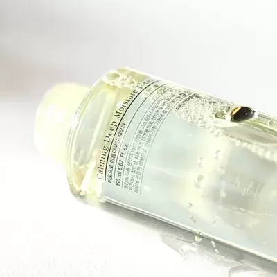Frasco transparente com rótulo em inglês e coreano sobre superfície branca