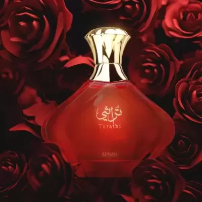 Frasco vermelho de perfume com tampa dourada entre rosas vermelhas