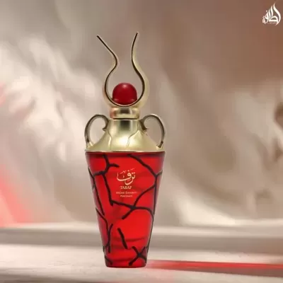 Frasco de perfume vermelho com tampa dourada decorativa e inscrições douradas no fundo bege.