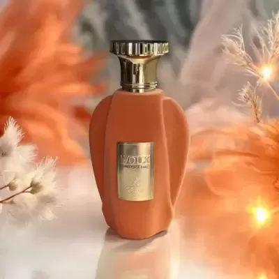 Frasco de perfume laranja com tampa dourada e placa metálica