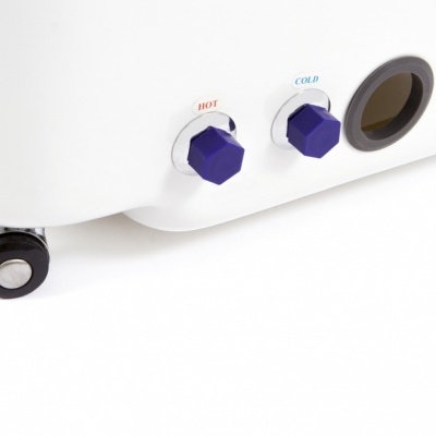 Aparelho branco com válvulas roxas HOT e COLD e tubo preto.