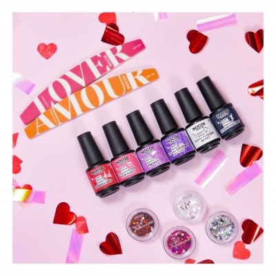 Conjunto de vernizes coloridos e glitter para unhas, decorado com corações e fitas sobre fundo rosa.