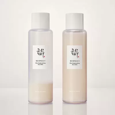Duas garrafas transparentes com produto líquido rotulado Glow Replenishing Rice Milk