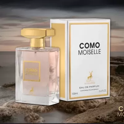 Frasco e caixa de perfume COMO MOISELLE sobre rocha com paisagem costeira ao entardecer