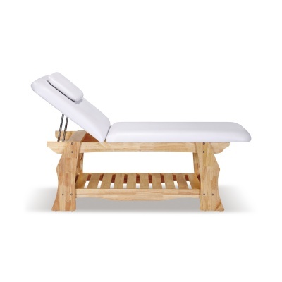 Cama de massagem com estrutura em madeira clara e almofada branca