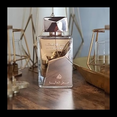 Frasco de perfume com líquido âmbar e tampa prateada numa mesa de madeira