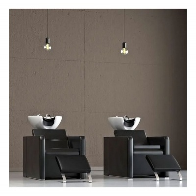 Dois cadeirões pretos com pias brancas para lavagem de cabelo, contra parede castanha com lâmpadas suspensas