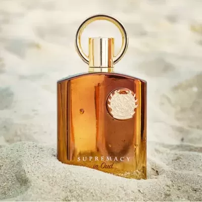 Frasco de perfume âmbar com tampa dourada na areia
