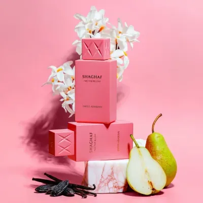 Frascos de perfume cor-de-rosa com flores, vagem de baunilha e peras ao lado