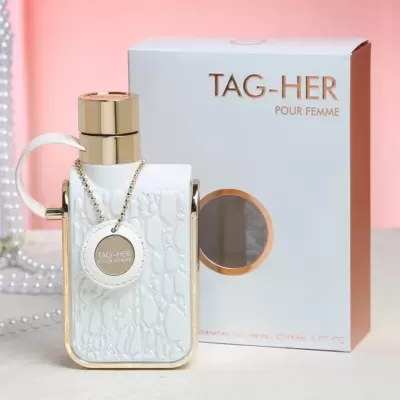 Frasco branco texturizado e dourado de perfume TAG-HER ao lado da caixa branca com texto dourado