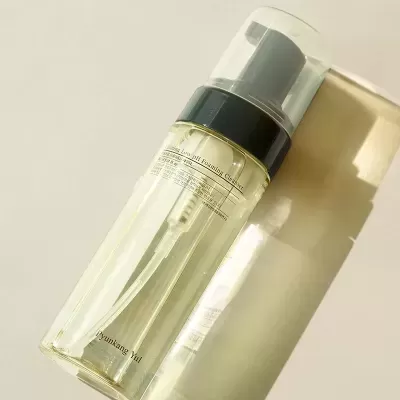 Frasco transparente com líquido amarelo claro e doseador para produto de limpeza facial