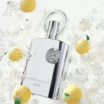 Frasco de perfume prateado entre flores brancas e limões amarelos