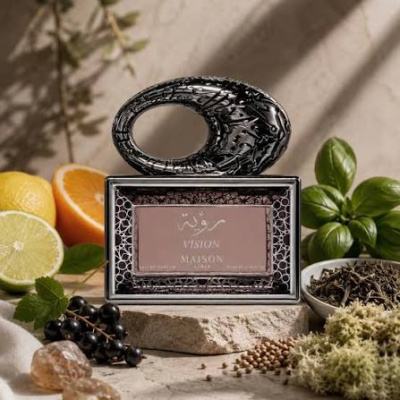 Frasco de perfume Vision Maison Paris com decoração preta e líquido rosa em cenário natural com frutas e plantas.