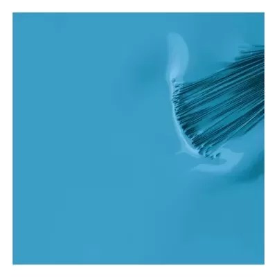 Pincel cosmético com cerdas finas sobre superfície azul