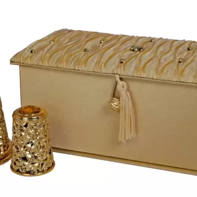 Frasco dourado de perfume com estojo bege texturizado e decorado