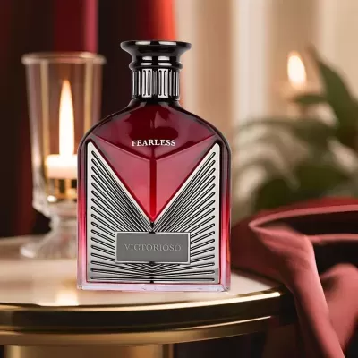 Frasco de perfume vermelho com detalhes prateados EM mesa com vela acesa