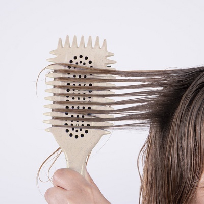 Escova de cabelo bege a pentear cabelo castanho liso molhado