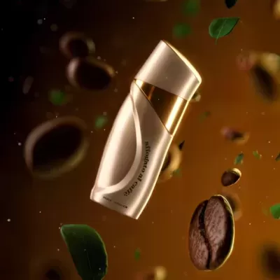 Frasco dourado e branco de perfume com grãos de café e folhas verdes ao fundo