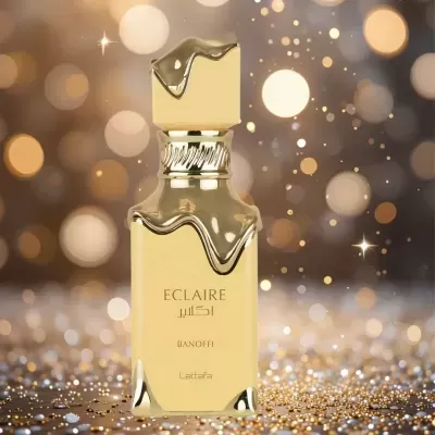 Frasco dourado de perfume ECLAIRE Banoffi sobre fundo dourado com luzes desfocadas