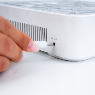 Dispositivo branco com entrada para cabo DC 12.6V e mão a inserir conector
