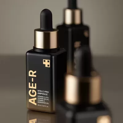 Frascos pretos com conta-gotas dourados de produto AGE-R VITA C PRO AMPOULE