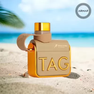 Frasco de perfume TAG Donna di Terra ARMAF na areia da praia