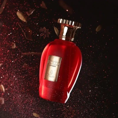 Frasco de perfume vermelho com etiqueta dourada em fundo escuro decorado