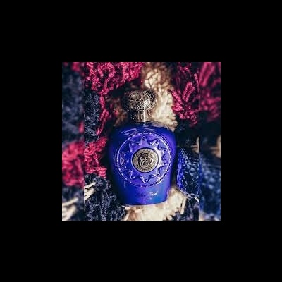 Frasco azul escuro com tampa dourada decorativa e tecido colorido ao fundo