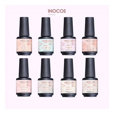 Sete frascos de verniz de unhas da coleção INOCOS com tampas pretas e rótulos pastel