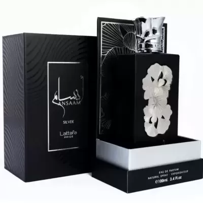 Frasco preto de perfume Ansaam Silver com decoração floral prateada ao lado de caixa preta com texto branco