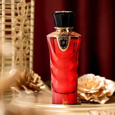 Frasco de perfume vermelho com tampa preta e detalhes dourados