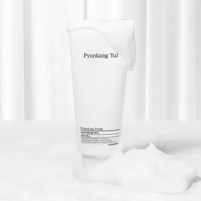 Embalagem branca de espuma de limpeza Pyunkang Yul com espuma branca sobre e ao lado, fundo branco