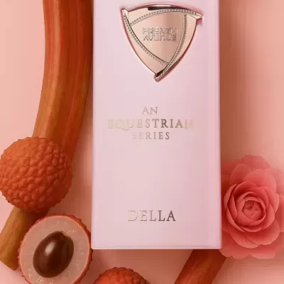 Frasco rosa claro de perfume com texto dourado e frutas laranja