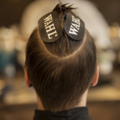 Cabeça vista de trás com cabelo castanho preso por fitas pretas WAHL num salão de cabeleireiro.
