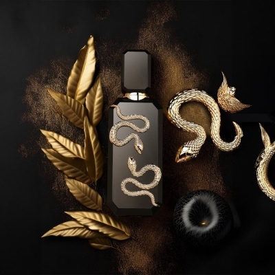 Frasco de perfume preto com serpente dourada e folhas douradas