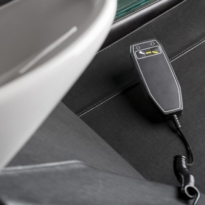 Comando remoto preto com dois botões amarelos sobre tecido preto com costura branca.