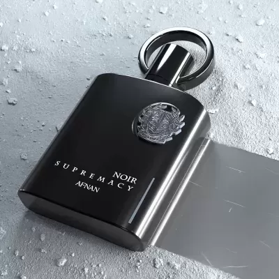 Frasco de perfume preto elegante com texto e emblema metálico em superfície cinzenta