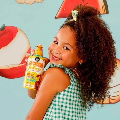 Criança com vestido verde aos quadrados brancos segura embalagem amarela de produto com texto FELICITY.