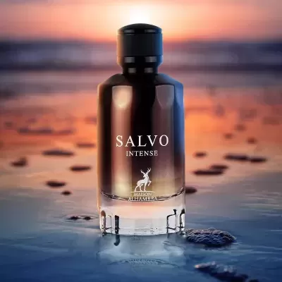 Frasco de perfume preto e transparente com inscrição branca numa superfície molhada ao pôr do sol
