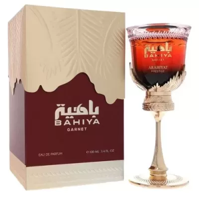 Frasco de perfume Bahiya Garnet com embalagem em vinho e bege, frasco em vidro vermelho sobre suporte dourado.