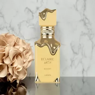 Frasco de perfume dourado elegante em superfície espelhada com flor ao lado e fundo de mármore
