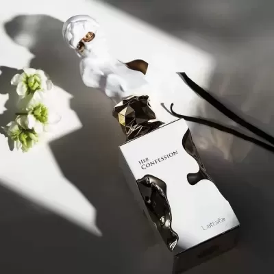 Frasco de perfume branco e dourado com flores e varas pretas