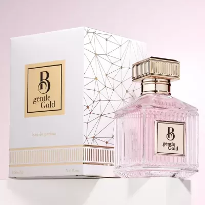 Frasco de perfume rosa translúcido com tampa dourada ao lado de caixa branca com detalhes dourados