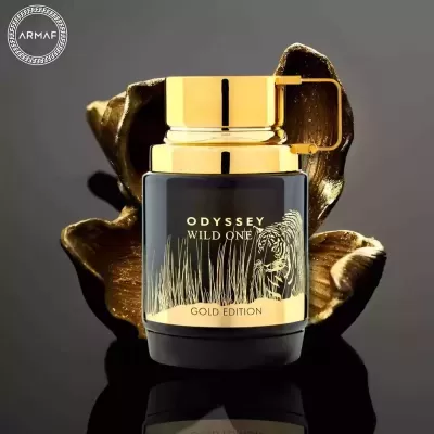 Frasco de perfume preto e dourado Odyssey Wild One Gold Edition sobre flor dourada