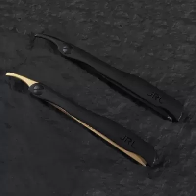 Dois aparelhos de barbear pretos com detalhe em bege sobre superfície preta texturizada