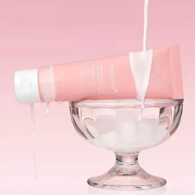 Tubo de creme hidratante rosa em taça de vidro, com creme a escorrer