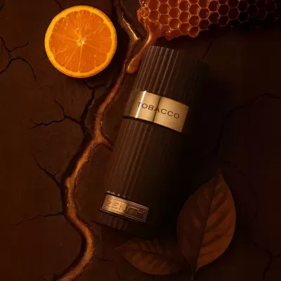 Frasco castanho escuro com etiquetas metálicas junto a fatia de laranja, favos de mel e folhas castanhas