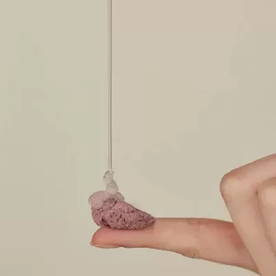 Dedo com pedaço roxo e gotas de líquido transparente a cair