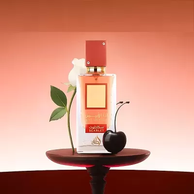 Frasco de perfume Scarlet com flor branca e cereja preta sobre prato vermelho