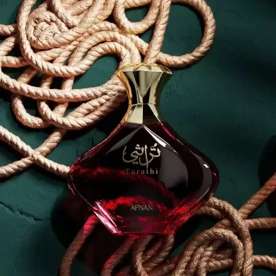 Frasco de perfume vermelho escuro com tampa dourada sobre cordas bege